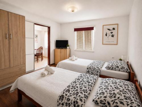 a bedroom with two beds and a television in it at Sunshine in Cavtat