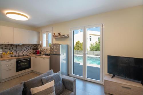 a kitchen with a living room with a refrigerator and a tv at Exis Seaview in Vathí