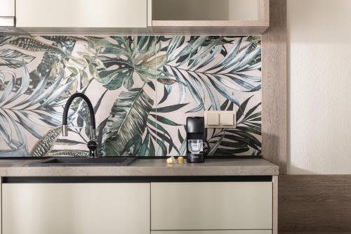 a kitchen with a sink and a tropical wallpaper at KLG Studios and Apartment in Nikiti
