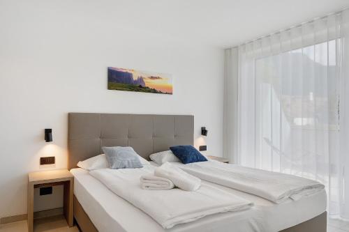 a bedroom with a large white bed with two towels on it at Bike Apartments Curti - Himmelblau in Laives