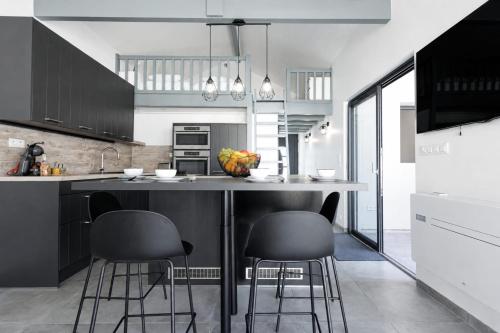a kitchen with black cabinets and a counter with stools at Cozy Cottage with Spa - Welkeys in Moliets-et-Maa