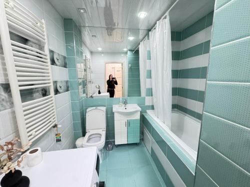 a person taking a picture of a bathroom with blue tiles at RentDay Botanica in Chişinău