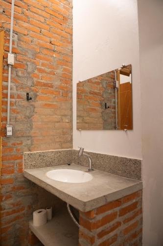 a bathroom with a sink and a brick wall at Pousada Corujas in Cajuru do Sul