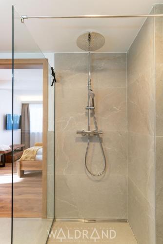 a shower with a glass door in a bedroom at Waldrand Apartments - by myNests in Ramsau am Dachstein