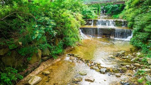 a river with a waterfall and a bridge over it at Goesan Jakeun Saejae Pension in Koesan