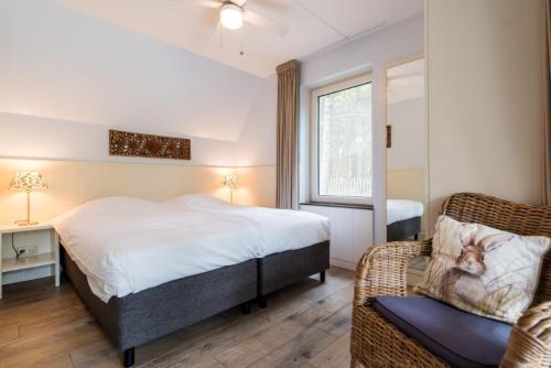 a bedroom with a bed and a chair and a window at Alegria, ruime familievilla voor 9 personen in Ballum