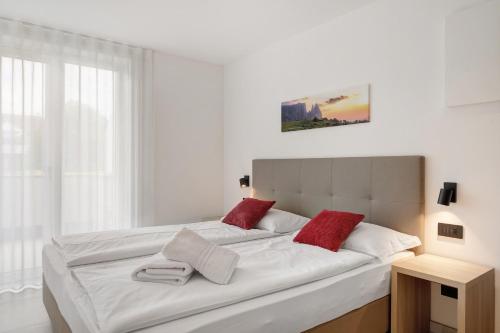 a bedroom with a large white bed with red pillows at Bike Apartments Curti - Abendrot in Laives