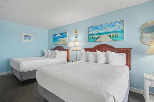 two beds in a hotel room with blue walls at The Patricia Grand in Myrtle Beach