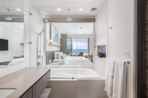a white bathroom with a tub and a large mirror at Clarita's Beach Bar & Resort, WorldHotels Elite in Jacó