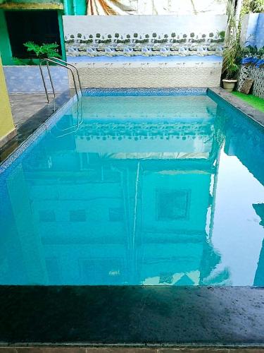 a blue swimming pool with its reflection in the water at Green Didis Cottage in Nagaon