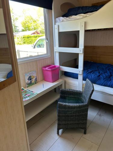 a bedroom with bunk beds and a chair and a window at Beach Resort Kamperland - 1123 in Kamperland