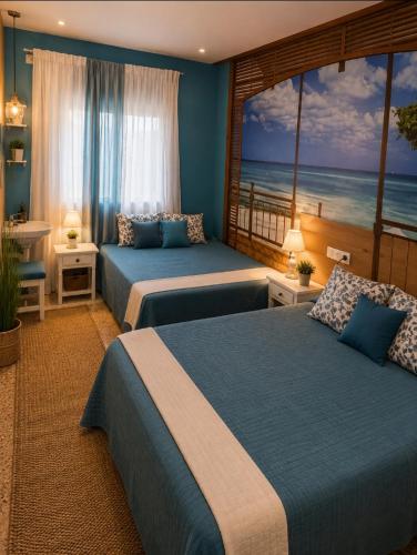 two beds in a room with a view of the ocean at Hostal Bernareggi in Cala Figuera
