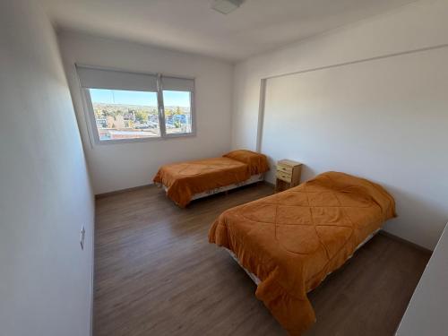 a bedroom with two beds and a window at LuxApart in Caleta Olivia