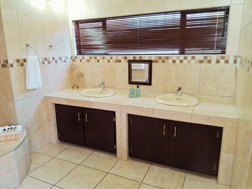 a bathroom with two sinks and a window at 30 on Latham Guesthouse in Klerksdorp
