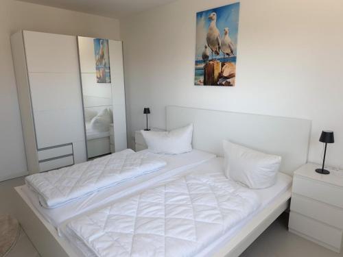 a white bedroom with a large bed with white pillows at Haus am Wittenwiewerbarg in Dahme