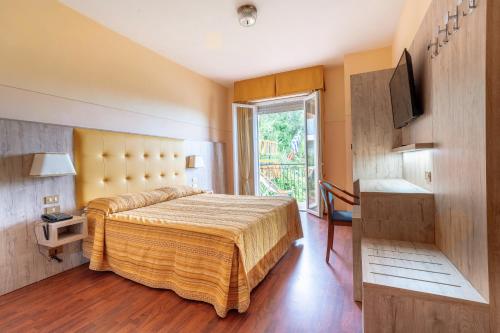 a bedroom with a bed and a tv and a window at Hotel Tirreno in Lavagna