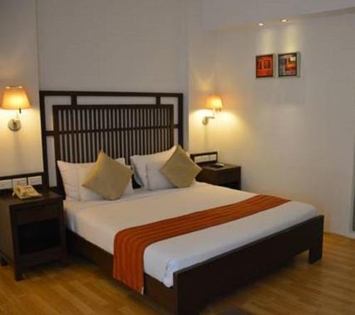 Un dormitorio con una cama grande con dos mesas y dos lámparas. en Hotel Natraj, en Dibrugarh