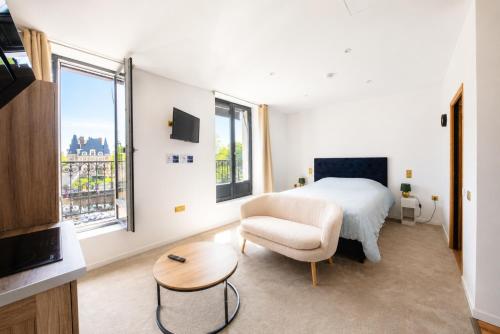 a bedroom with a bed and a chair and window at HDG Hôtel Gare de L'Isle Adam Appart's Hotel in Parmain