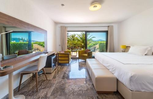 a hotel room with a bed and a desk and a window at Kalkan Regency in Kalkan