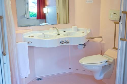 uma casa de banho com um lavatório branco e um WC. em Première Classe Clermont-Ferrand Aubière em Aubière