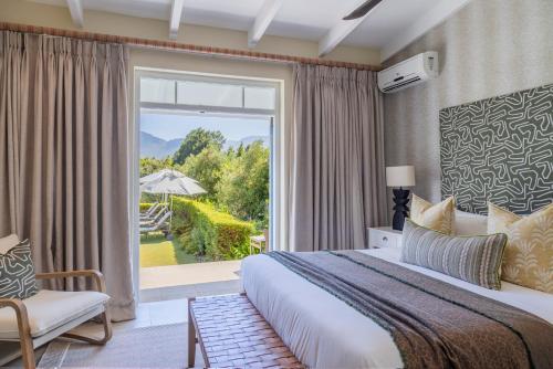 a bedroom with a bed and a large window at La Cabriere Country House in Franschhoek