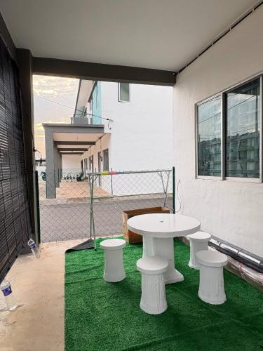 a white table and two stools on a green floor at Arowana Homestay MALAY ONLY in Sungai Petani