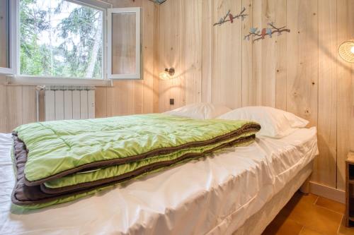a bedroom with a bed with a green comforter on it at Camping les Pialades - Gite in Nabirat