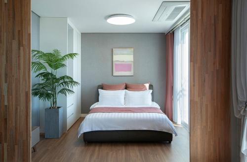 a bedroom with a bed and a potted plant at Yeongduk Brie Pension in Yŏngdŏk