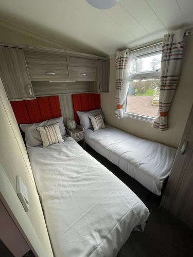 two beds in a small room with a window at Linnet Moselle 5 in Peterhead