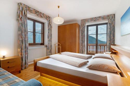 a bedroom with two beds and two windows at Gschtraffhof in Kastelruth