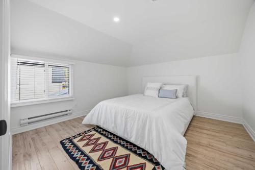 a white bedroom with a bed and a window at Lake Drive apartment in Georgina