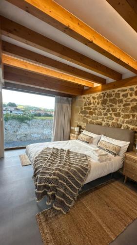 a bedroom with a large bed with a stone wall at Casona de Queveda in Queveda
