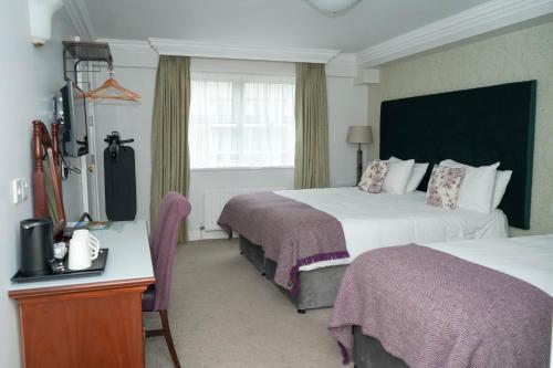 a hotel room with two beds and a television at Nesbitt Arms Boutique Hotel in Ardara