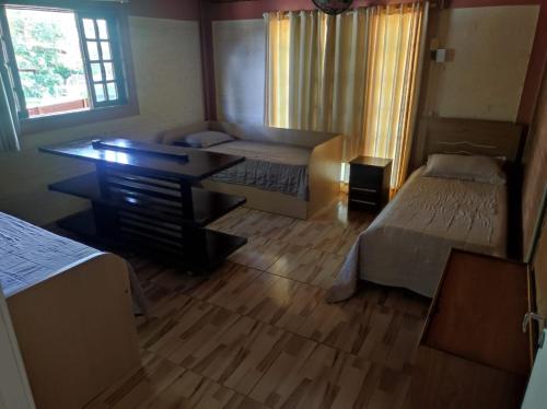 a room with two beds and a desk in it at Hostel Oasis Jaguariuna in Jaguariúna