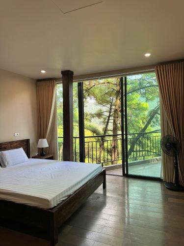 a bedroom with a large bed and a balcony at DeBay Retreat - Little Đà Lạt Chill Villa in Sóc Sơn