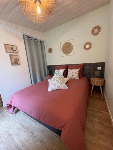 a bedroom with a large bed with a red comforter at Le Logis du Coteau in Bellefoye