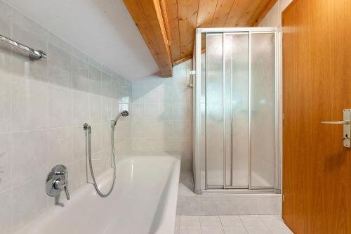 a bathroom with a shower and a white bath tub at Gschtraffhof in Kastelruth
