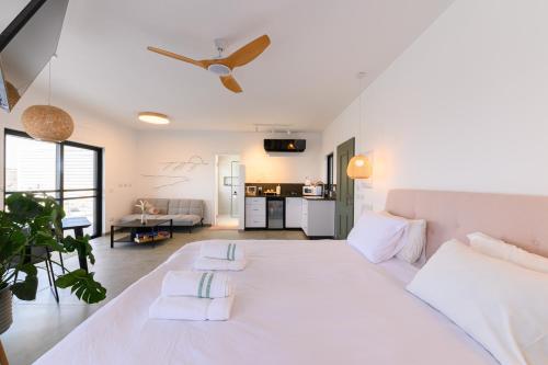 a bedroom with a large white bed with a ceiling fan at ציפור הכנרת - סוויטה מבודדת נוף לכנרת in Had Nes