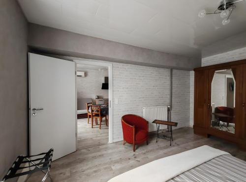 a bedroom with a red chair and a dining room at Domaine Du Hêtre - Meublé T2 in Bains-les-Bains