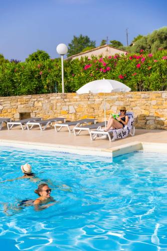 two people sitting in chairs in a swimming pool at Le Cyprès - La Fontinelle in Bessas