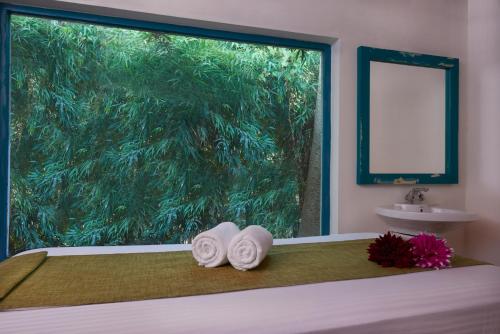 a bedroom with two towels on a bed with a window at Aacorn Hideaway Resort & Spa in Rāmnagar