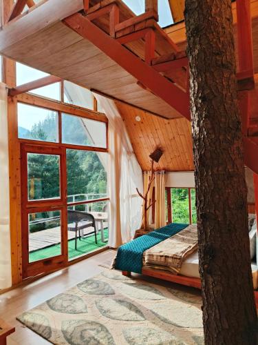 a bedroom with a bed and a large window at jibhihomesteadcabin in Jibhi