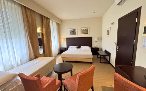 a hotel room with a bed and a table and chairs at Hotel Terme in Monticelli Terme