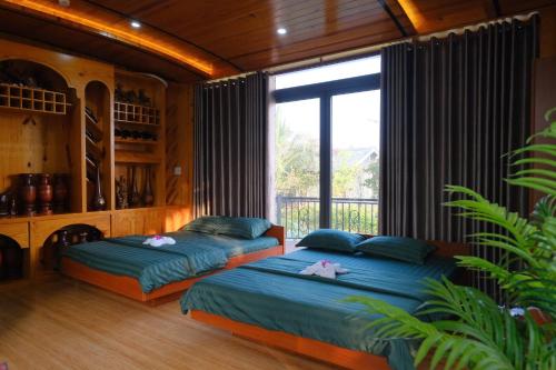 two beds in a room with a large window at Cafe cắm trại Đồng Gió Phước Hải in Xã Long Mỹ