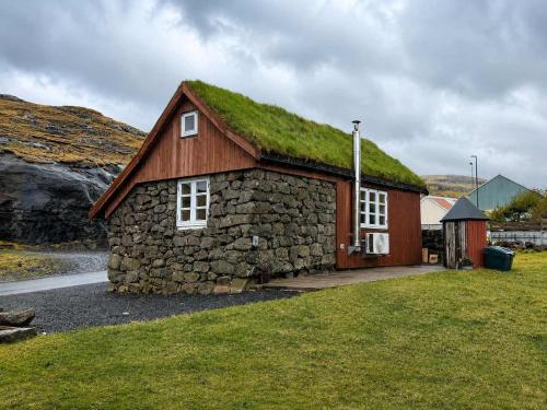 a building with a grass roof on a field at Traditional Cabin with Sea View in Stykkið