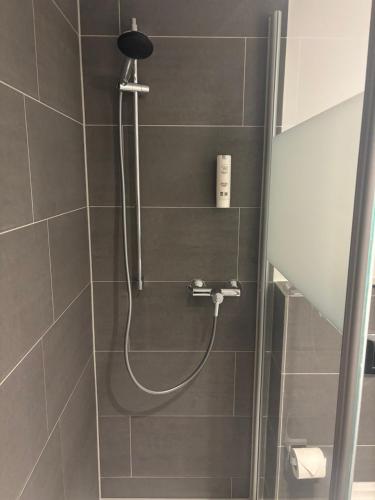 a shower with a shower head in a bathroom at MY STAY - Smart Hotel in Mönchengladbach