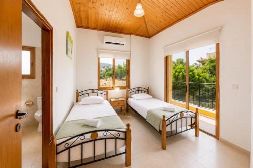 two beds in a room with a window at Villa Androulla in Argaka