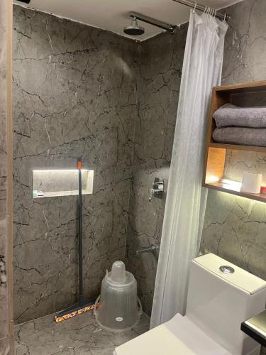 a bathroom with a shower curtain and a toilet at Aariv Inn BAGA BEACH in Baga