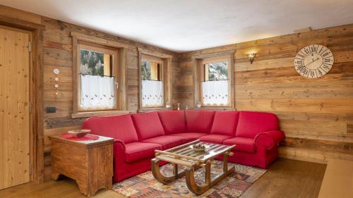 a red couch in a room with a clock on the wall at Chalet Sozzine in Ponte di Legno