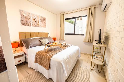 a small bedroom with a bed and a tv at Apartamento com Café no 1º Dia, Kit Fondue e Aquecedor no Quarto a 300m da Praia para Casais in Imbituba